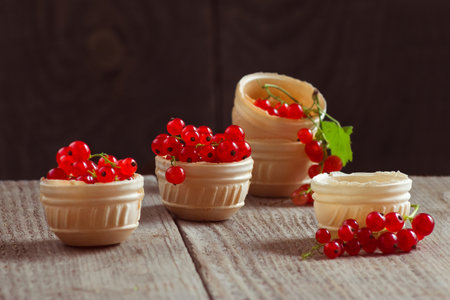 Bunches of red currants in waffle plates on a wooden table. Still life with berries filled with vitaminsの写真素材