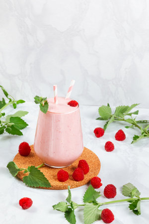 Milkshake with raspberries in a glass glass with melissa leaves in the design with copy spaceの写真素材