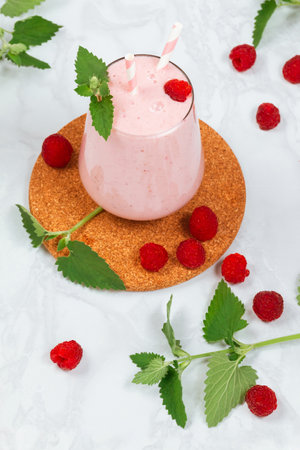 Milkshake with raspberries in a glass glass with melissa leaves in the designの写真素材
