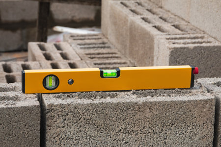 The bubble construction level lies on a cinder block construction stone. It is used to assess the compliance of surfaces with a vertical or horizontal plane, as well as to measure the angular deviatioの写真素材