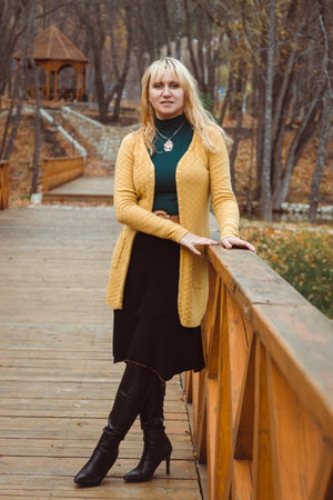 A young woman in autumn on the bridge looks aheadの写真素材
