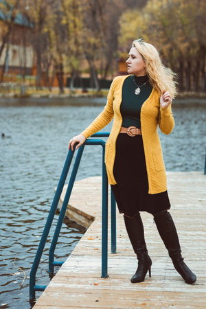 Young woman in autumn on the pier looks awayの写真素材