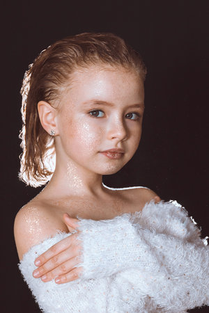 Beautiful portrait of a model girl in a white blouse with sequins on the skin on a black backgroundの写真素材
