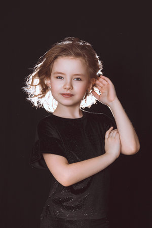 Girl model in black clothes with flying hair on a black backgroundの写真素材