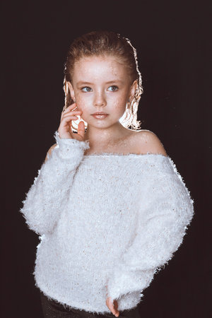 A model girl in a white blouse with sequins on her skin poses on a black backgroundの写真素材