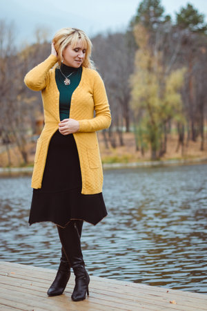 A young woman in autumn on the pier looks down and adjusts her hairの写真素材