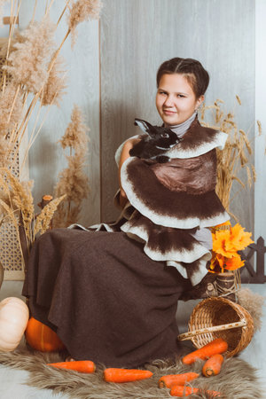 A girl hugs a black rabbit in an autumn rustic-style sceneryの写真素材