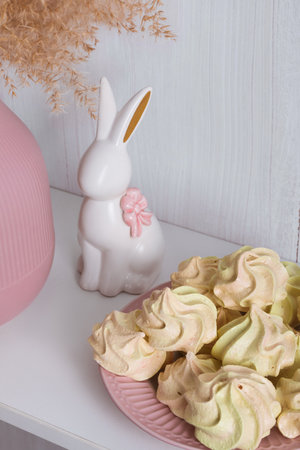 Yellow-pink meringue on a pink plate and a white porcelain rabbit with a bowの写真素材