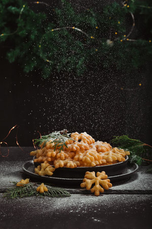 Cookies Brushwood in the form of snowflakes, sprinkled with powdered sugar, lies in a pile on a black plate, with copy space. Delicious, tender and crunchy treat for the holidayの写真素材