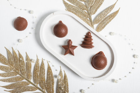 Chocolate in the shape of Christmas tree toys on a white background with elements of Christmas decorations. A postcard for the New Yearの写真素材