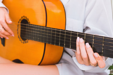 A woman in a white shirt plays the guitar, close-upの写真素材