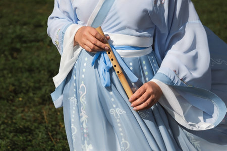 A woman in a traditional Chinese hanfu dress holds a bamboo flute close-upの写真素材
