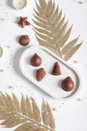 Chocolate in the shape of Christmas tree toys on a white background with elements of Christmas decorations. A postcard for the New Yearの写真素材