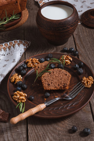 Rustic festive table setting with chocolate cupcake slices, walnuts, blueberries and milkの写真素材