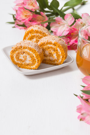 Festive sweet treat rich in vitamins and fiber, carrot and pumpkin roll on a white background with a copy spaceの写真素材