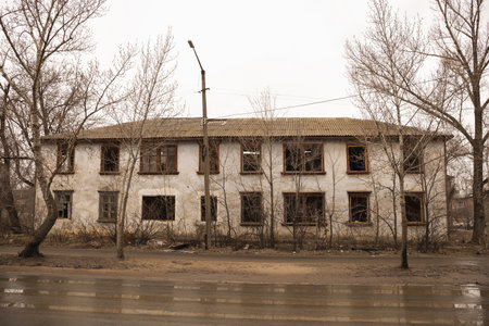 An old two storey house, partially without windows in early spring in rainy weatherの写真素材