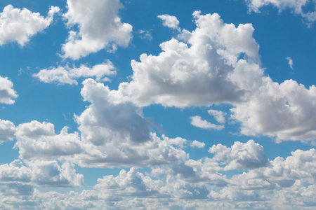 Fluffy white clouds scatter across a bright blue sky, creating a peaceful and serene atmosphere ideal for themes of tranquility and nature. Perfect for backgrounds or nature scenesの写真素材