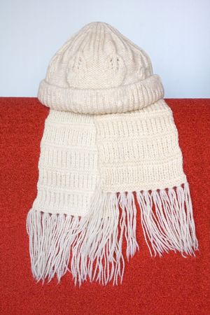 Knitted cap and comforter over red.の写真素材