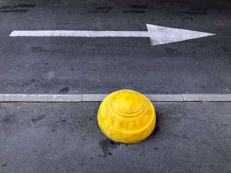 Yellow Concrete Hemisphere. Parking limiter and road arrow direction sign on asphalt. Anti-parking...