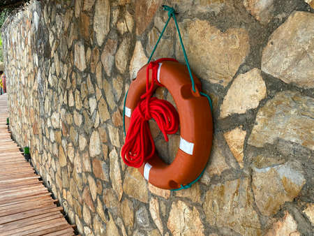 Red lifebuoy with rope hanging on the stone wall. Water rescue equipmentの写真素材