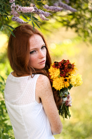 Beautiful red hair bride with bright bouquet of daisies outdoors, on forest. Toning and softnessの写真素材