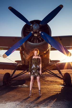 Woman with red hair in military clothes near the aircraftの写真素材
