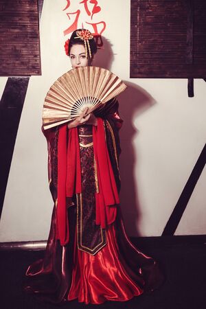 young pretty geisha in kimono with sakura and decoration, with samurai swordの写真素材