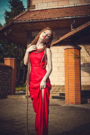 Young sexy woman floating on swimming pool in red dress. Beautiful rich lady who was strangled and thrown off into the water, but she is aliveの写真素材