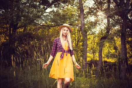 Attractive young woman enjoying her time outside in park with sunset in background.
