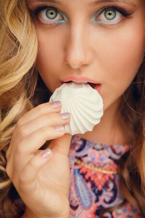 A lovely young girl with blond hair eating dessert and drinking tea in a cafeの写真素材
