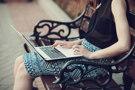 Young woman using tablet, laptop, notebook, reading books outdoor, smiling.の写真素材