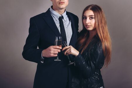 Portrait young couple with glass of champagne, wear evening dress and suit, glamour vogue style, sensual looking at camera, sitting indoorsの写真素材
