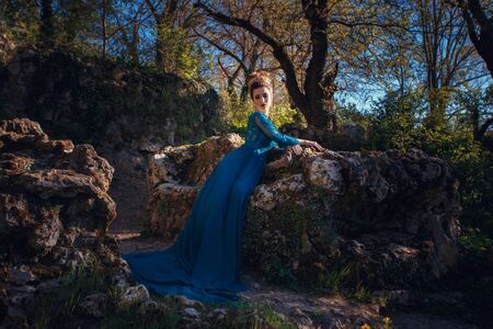 Beauty woman in green luxury expensive dress and in crown on the nature. Beautiful model girl in a green wedding dress. Female portrait in the park. Cute lady outdoors. Fashion style portraitの写真素材