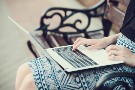 Young woman using tablet, laptop, notebook, reading books outdoor, smiling.の写真素材
