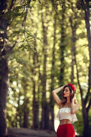 beautiful young brunette woman in a Park at sunset with flower wreath. summer timeの写真素材