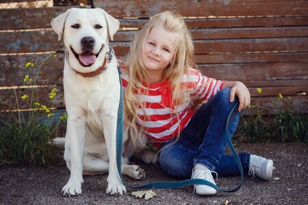 Beautiful blonde girl playing with her dog. Outdoor portrait. seriesの写真素材