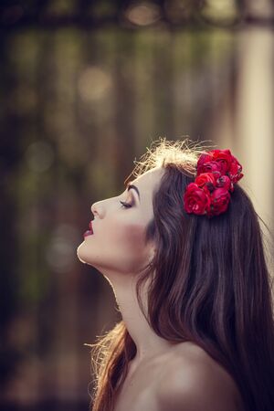 beautiful young brunette woman in a Park at sunset with flower wreath. summer timeの写真素材