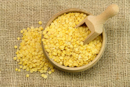 Yellow Lentils, wooden cup and spoon on sackcloth