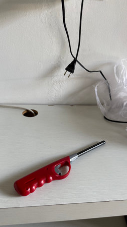 Red Long Lighter on White Desk with Black Wires and Unplugged Cable