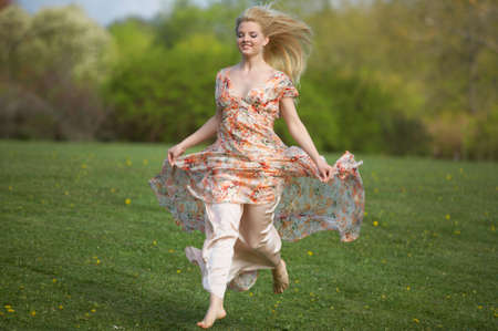 Happy beautiful young woman jumping (running) on meadowの写真素材