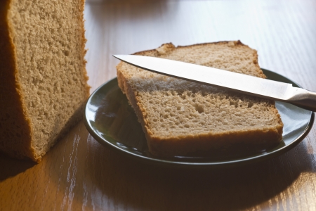 The cut bread lies on a plate together with a knife