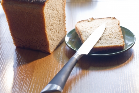 The cut bread lies on a plate together with a knife
