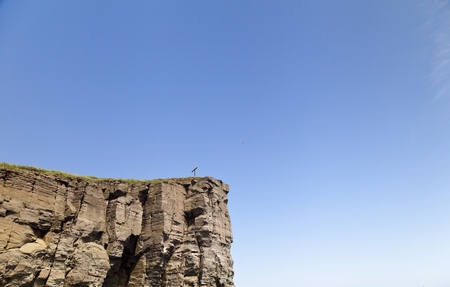 The cross on the rock over the sea meets floating shipsの写真素材