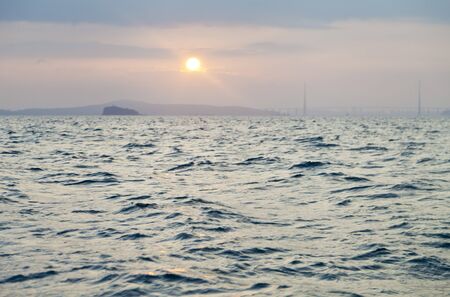 The sun sits down in the evening sea far in the Westの写真素材