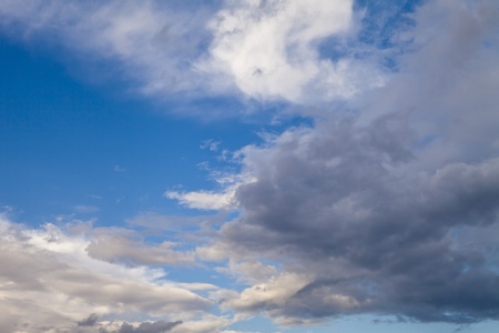 Black clouds in the blue sky in beams of the bright evening sun