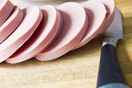 The cut sausage lies on a table together with a knife waiting for eatersの写真素材