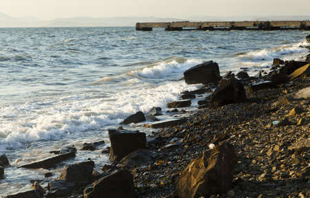 Sea surf at sunset in beams of the setting sun