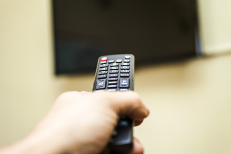 Remote control in hands is going to turn on the TVの写真素材