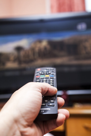 Remote control in a hand is going to change channelsの写真素材