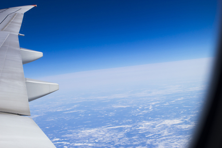Plane wing against the bright blue sky in flightの写真素材
